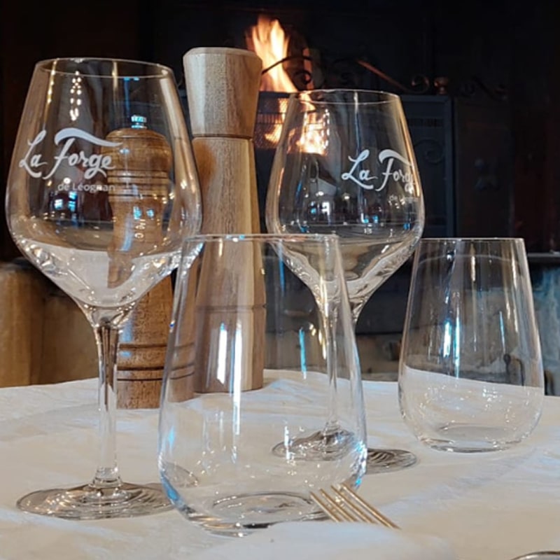 La Forge de Léognan: Verres de vin et ambiance cheminée Table avec verres La Forge de Léognan, moulin à poivre, et cheminée allumée en arrière-plan. Ambiance chaleureuse.